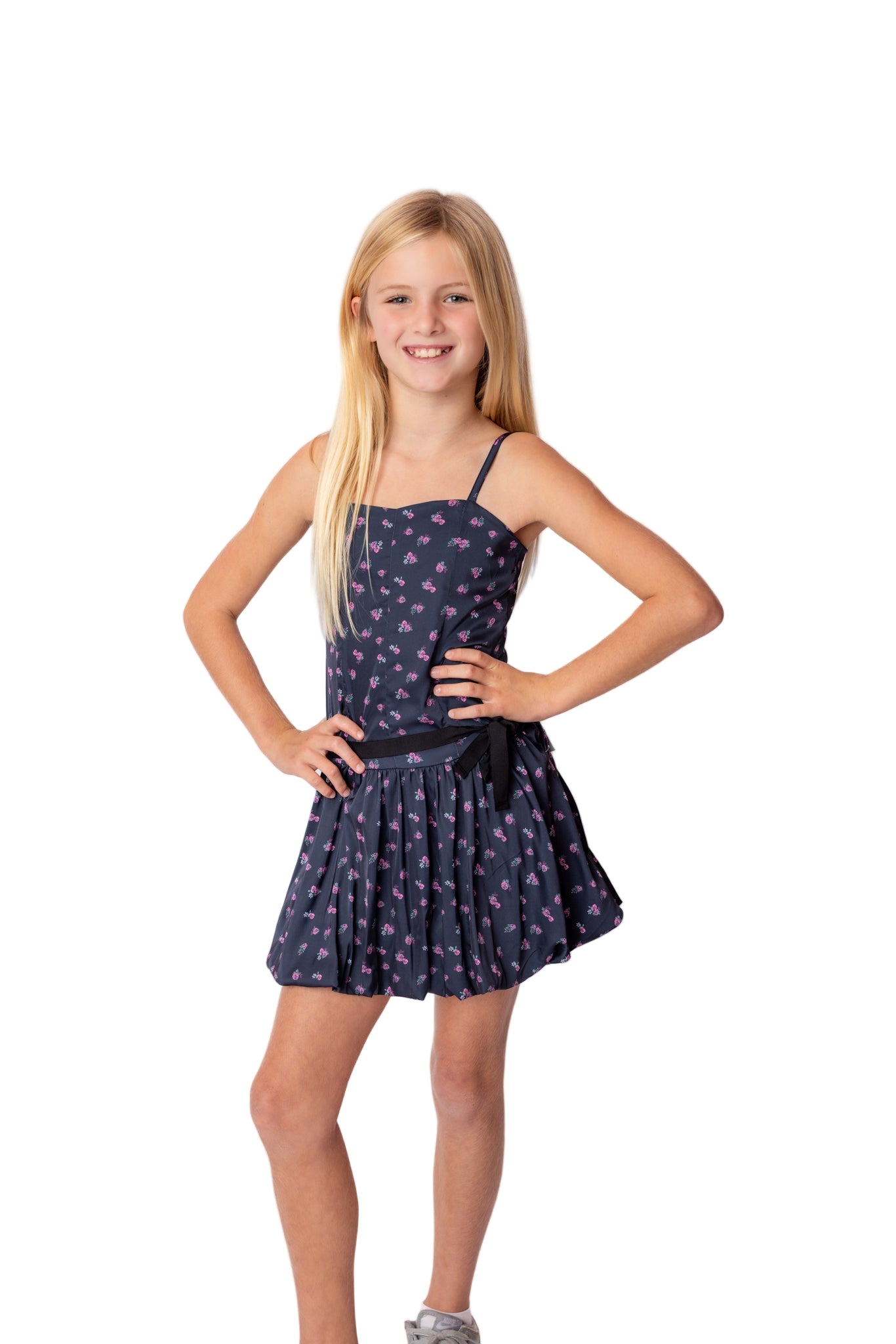 Young girl wearing a navy blue dress with white patterns on a white background