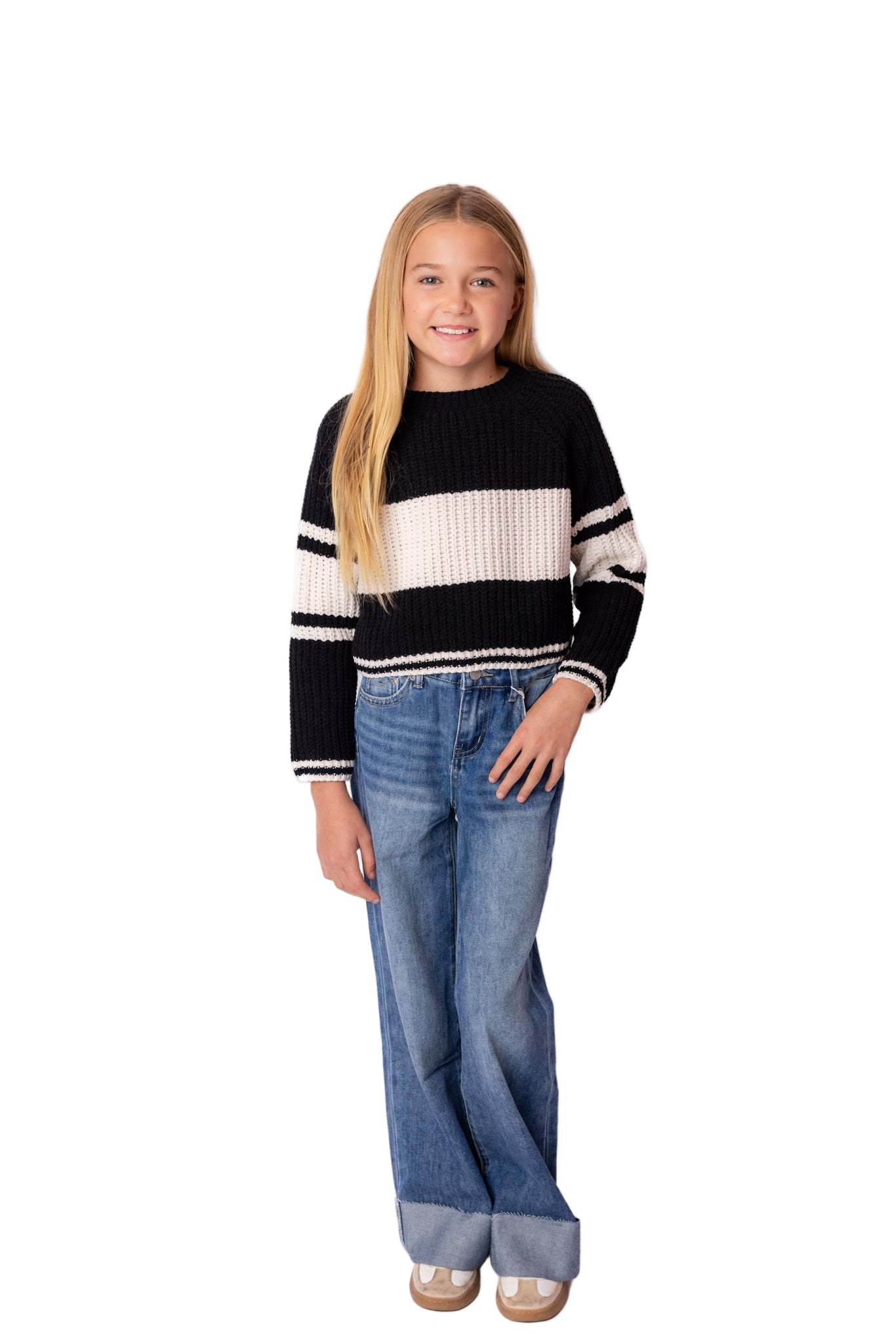 Young girl wearing a black and white striped sweater and blue jeans on a white background