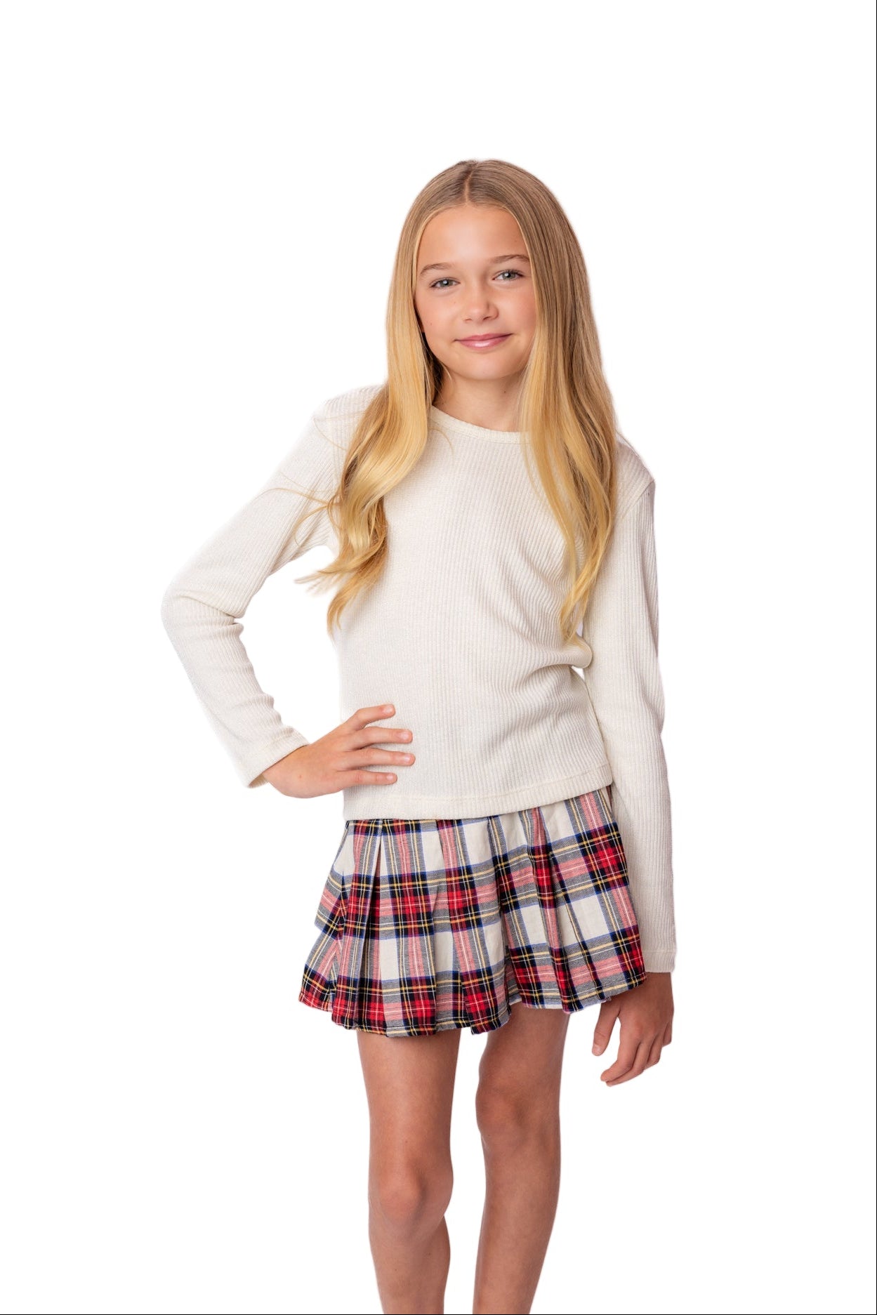 Young girl wearing a white long-sleeve shirt and plaid skirt on a white background