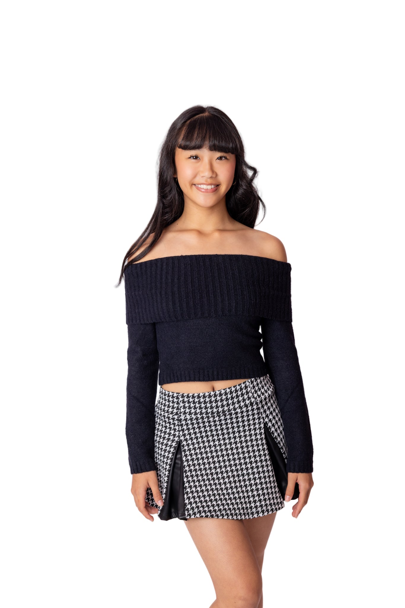 Woman wearing a black off-shoulder top and houndstooth skirt on a white background