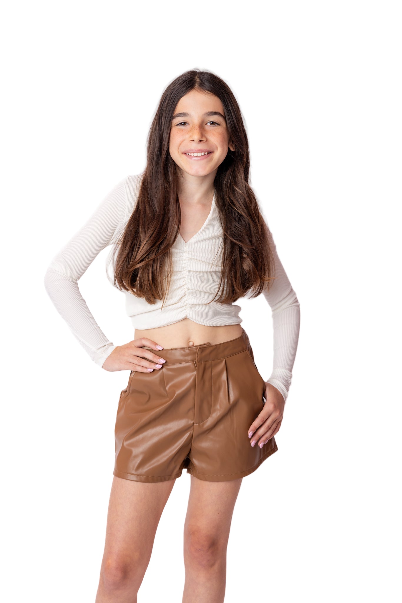 Person wearing a white long-sleeve top and brown leather shorts on a white background