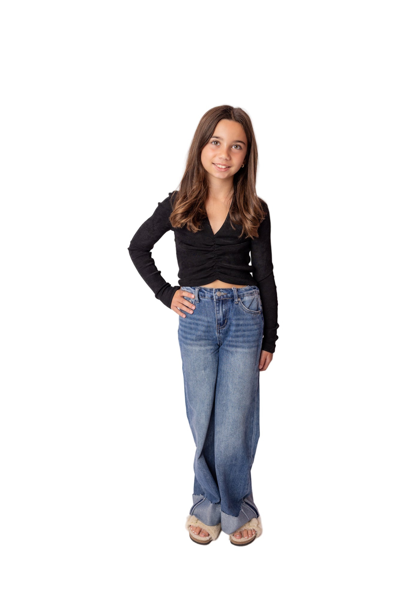 Person wearing a black long-sleeve top and blue jeans on a white background