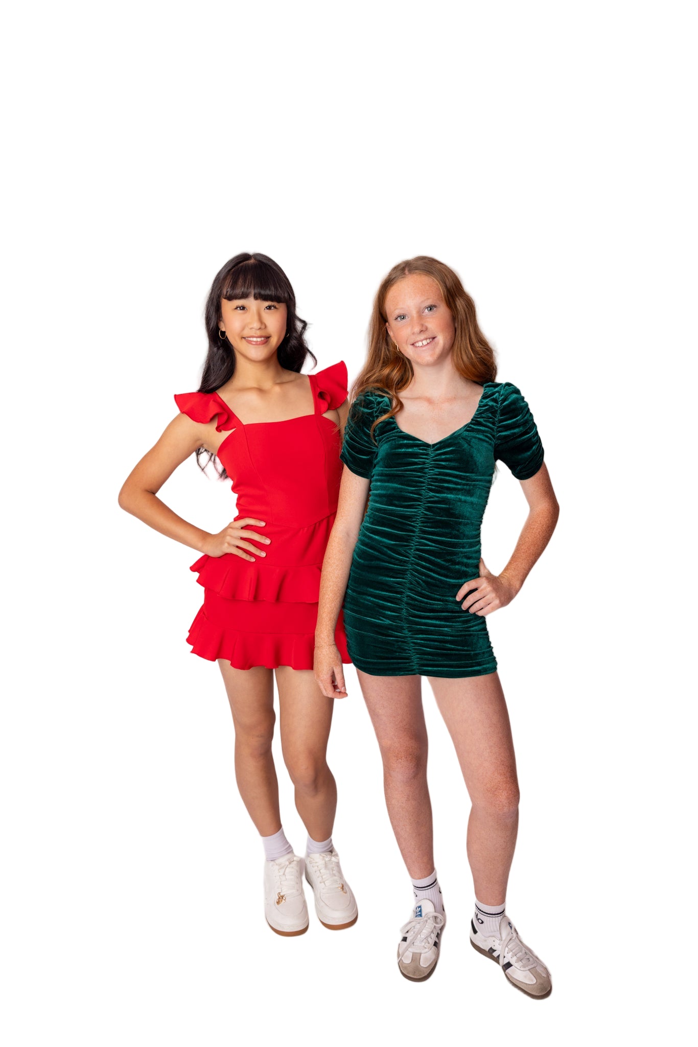 Two women wearing red and green dresses standing against a white background