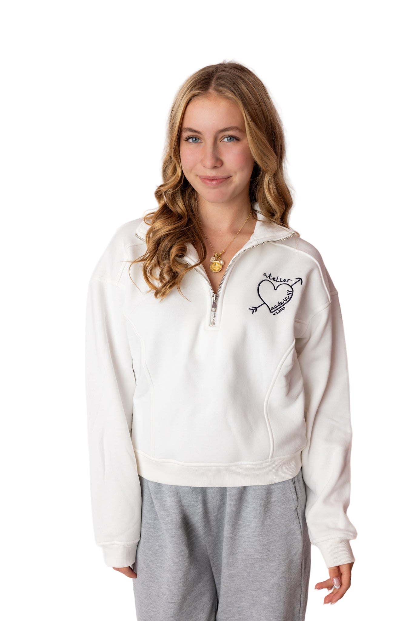 Woman wearing a white zip-up sweatshirt with a design on the chest against a white background