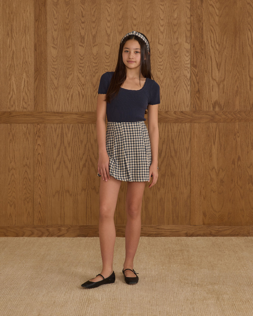 Young girl wearing a navy top and checkered skirt from Leypop Shop designed by KatieJ NYC